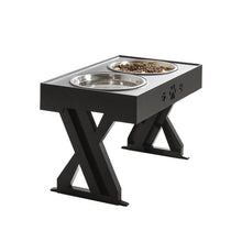 Cargar imagen en el visor de la galería, Stylish black pet feeding station with two stainless steel bowls, featuring paw print design and a sturdy X-shaped support that can be adjusted according to the pet&#39;s growth
